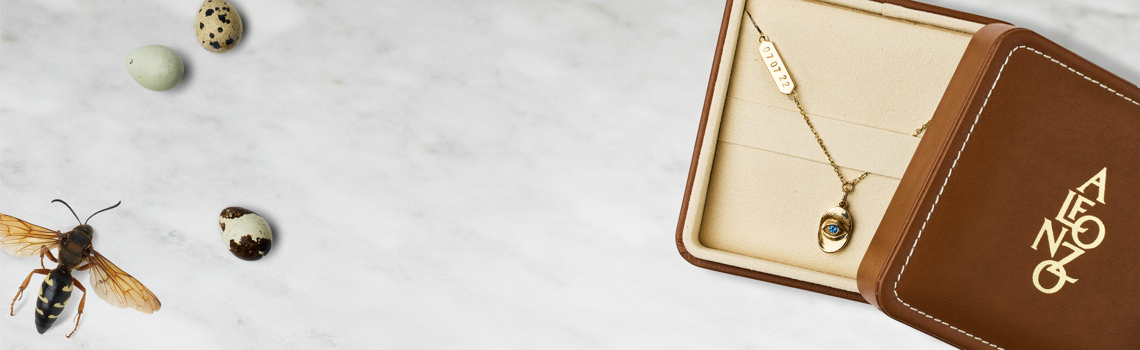 Open jewelry box with gold necklace, small stones, and insect on textured surface