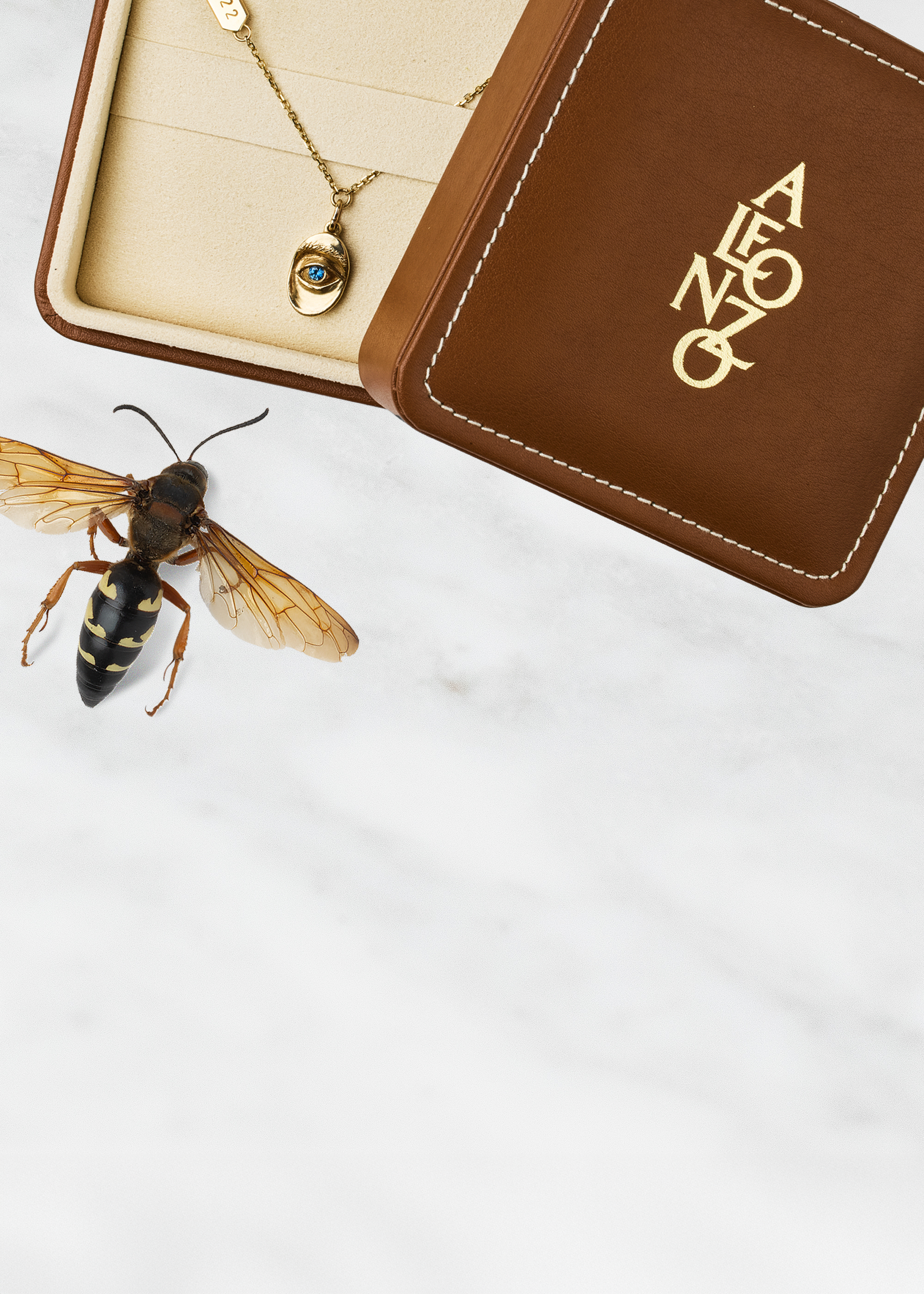 Close-up of a wasp on a white surface with a brown leather case featuring a  Alfonzo logo and a pendant by Alfonzo.
