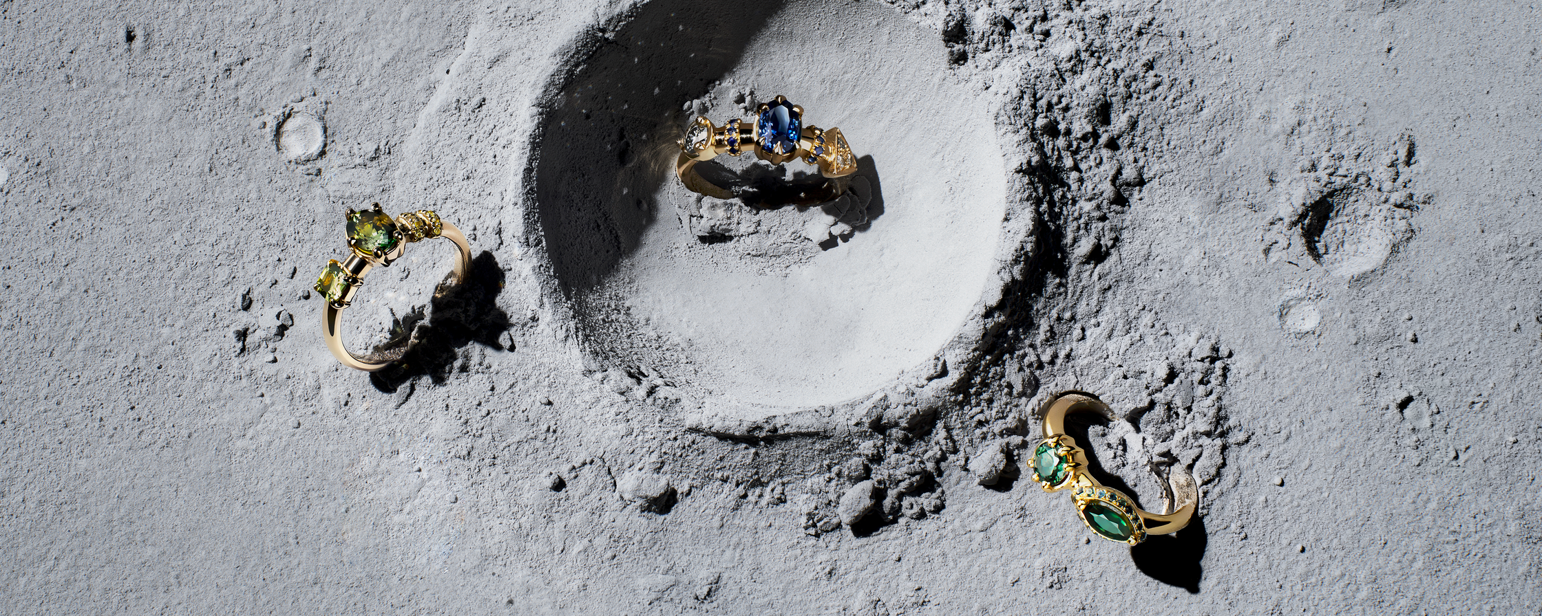 Three engagement rings on an abstract space like backdrop