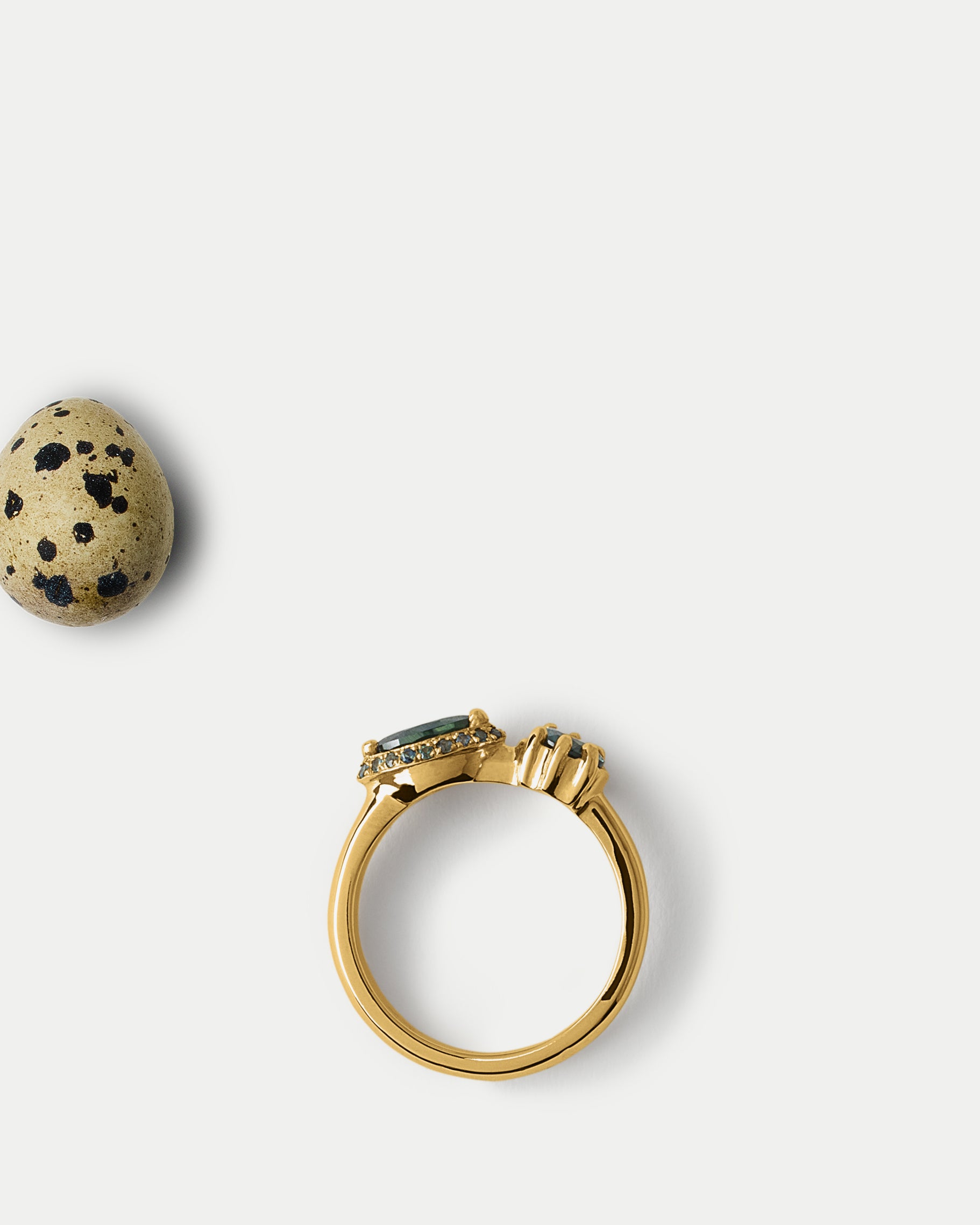 Flat lay view of Helix Ring ft. Teal Sapphires in 14k yellow gold with an egg
