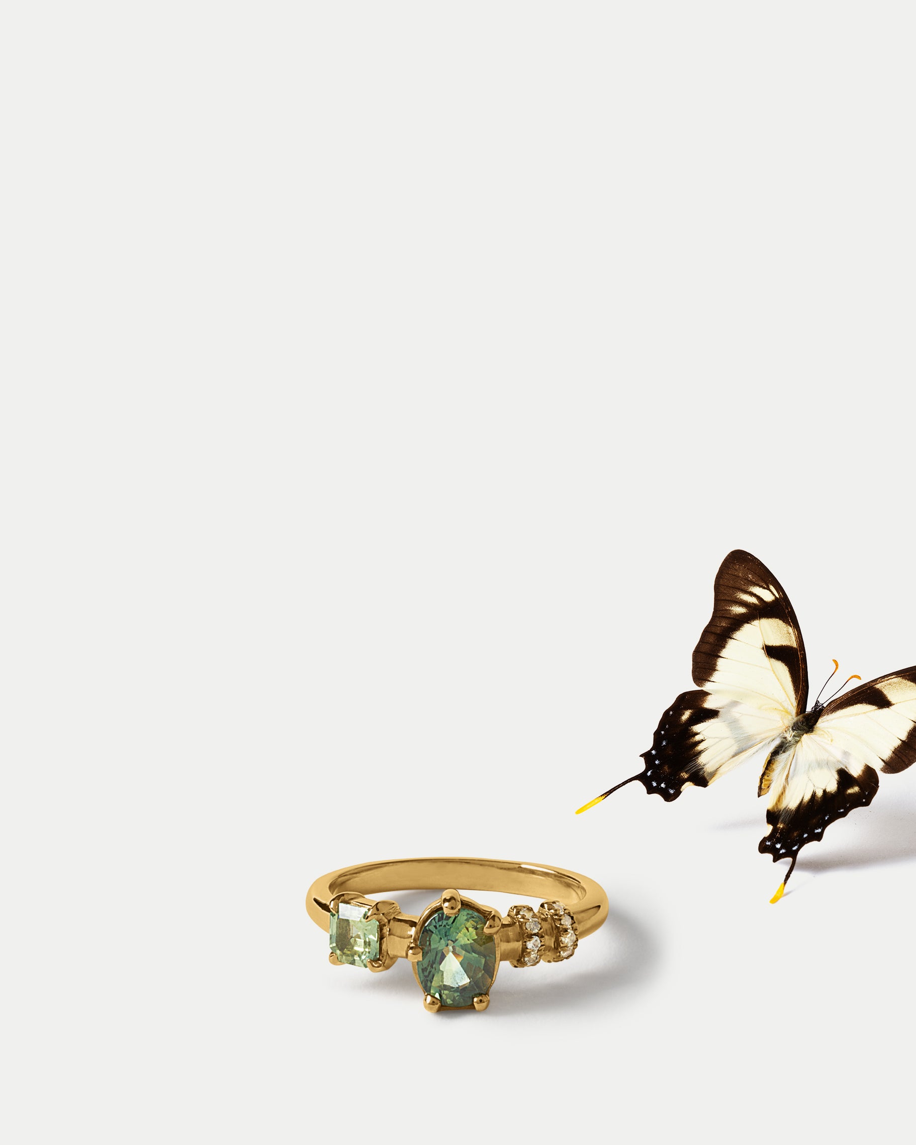 Angled view of Monoceros Ring ft. Oval Green Sapphire in 14k yellow gold with a butterfly