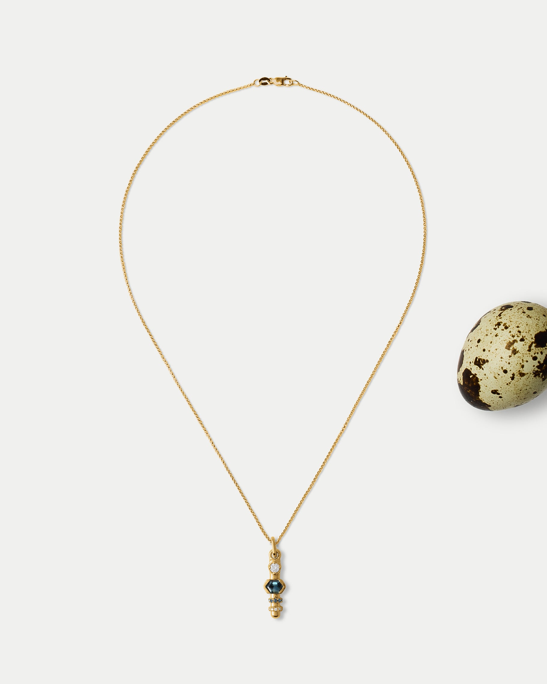 Front view of Monoceros Totem ft. Teal Sapphire & White Diamond in 14k yellow gold with an egg